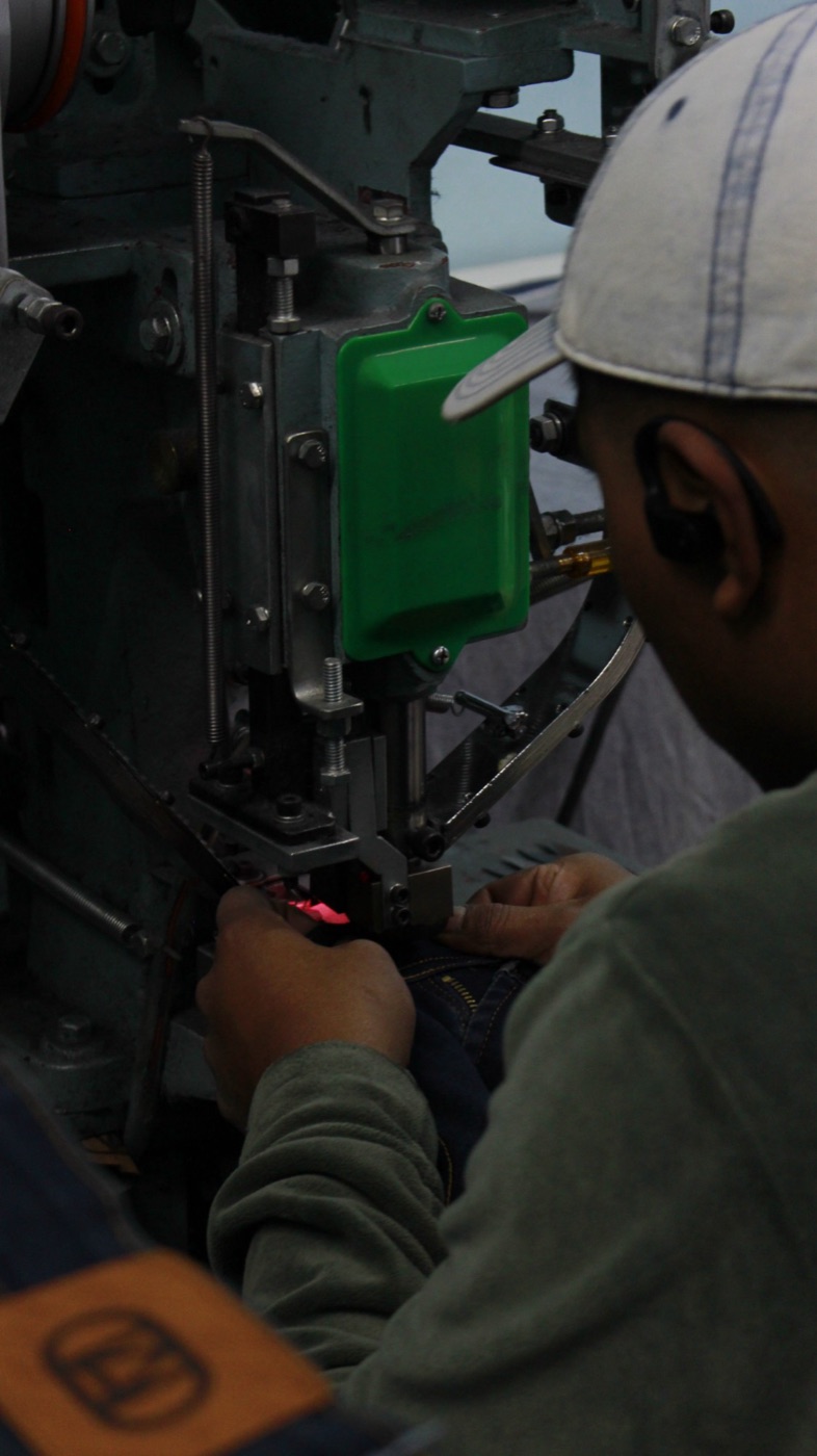 Operario trabajando en una máquina de terminación de jeans